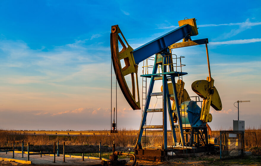 An oil well on a farm with a clear sky.