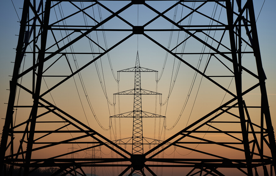 Powerlines through the base of a tower at sunset.
